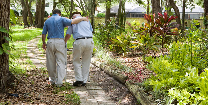 assisted living placement specialist with elderly man on walking path
